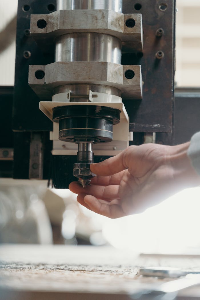 our-services-1 Detailed shot of a CNC machine spindle being adjusted by a human hand in a workshop setting.